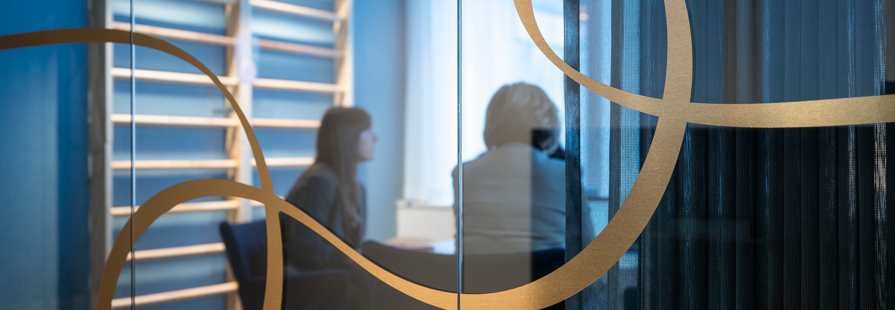 En kvinna sitter vid ett skrivbord framför en glasvägg.